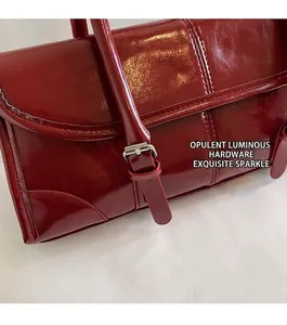 Detail of burgundy patent leather bag with vertical stitching and silver buckle