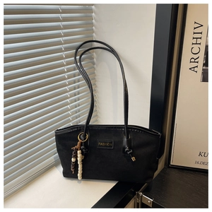 Close-up of black retro tote bag featuring long leather straps and wood bead tassel decoration