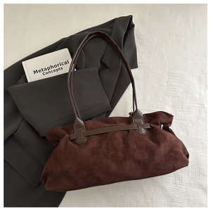 Flat lay view of a dark brown suede tote bag with leather straps and metal hardware
