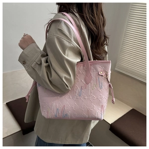 Close-up of pink tote bag with wavy embroidery patterns and leather shoulder straps