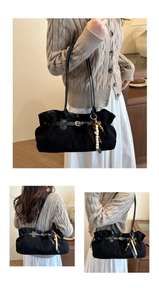 Detail of black suede tote bag featuring leather strap buckle and boho beaded keychain