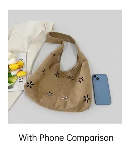 Détail du sac cabas en daim marron avec découpes florales à côté d'un smartphone