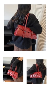 Detail of red patent leather shoulder bag with vintage silver buckle straps and glossy finish