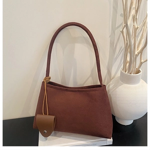 Detailed macro of brown suede shoulder bag with small heart pendant and metal stud