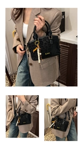 Dettaglio borsa nera con stampa leopardata, logo dorato e ciondolo con perline alla moda