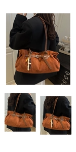 Close-up of vintage faux suede tote bag with decorative wooden beads and rustic metal buckle