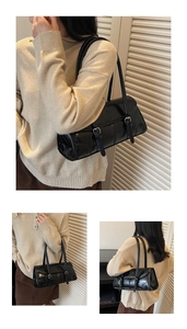 Detailed view of the black leather shoulder bag with dual buckle design and glossy finish