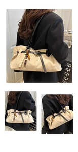 Detail of beige suede tote bag with black straps and decorative wooden bead charms