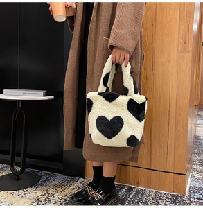 Detalle de un bolso de felpa suave con un diseño de corazón negro sobre piel sintética blanca