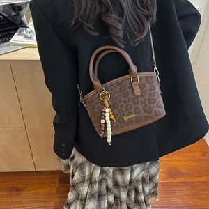 Chic leopard print bucket bag with wooden bead charm and long shoulder strap