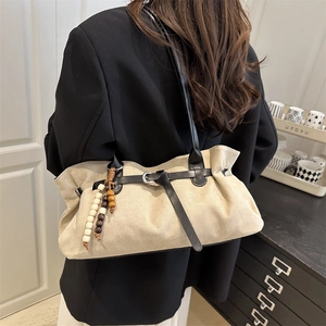 Vintage beige suede shoulder bag with black leather straps and wooden bead charm detail