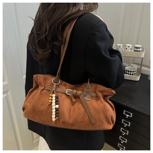 Detail van een bruine suède hobo tas met vintage houten kralen en een leren gesp detail