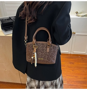 Detail of leopard print bucket bag with brown handles and elegant beaded charm tassel