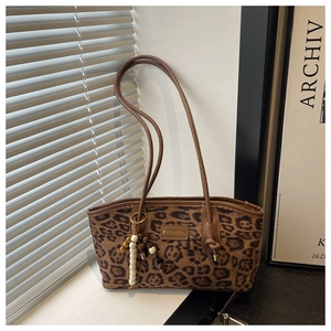 Detail of leopard print suede shoulder bag featuring a fashion tag and beaded charm