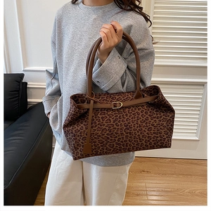 Close-up of leopard print canvas tote bag featuring brown leather straps and metal D-ring