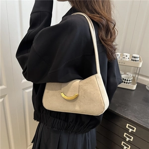 Minimalist beige suede shoulder bag with golden crescent moon buckle on a model