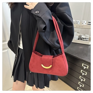 Red suede underarm bag with gold crescent buckle worn by a model in black outfit