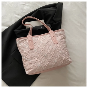 Détail d'un sac cabas rose avec broderie florale et texture plissée élégante