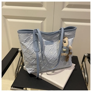 Dettaglio della borsa tote azzurra con ricami floreali e texture plissettata in 3D