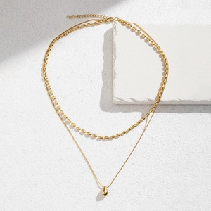 Detail of double-layer gold necklace featuring water drop pendant and beaded chain