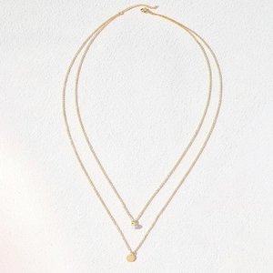 Elegant double layered gold necklace featuring a pearl pendant and minimalist round disc