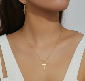 Détail du collier avec pendentif croix dorée et boucles d'oreilles assorties