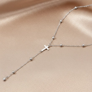 Polished stainless steel beaded cross necklace with pendant on champagne silk background