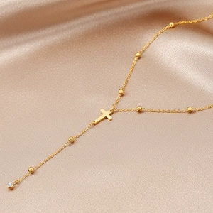 Detail of gold Y-shaped cross necklace with beads and sparkling zircon tassel on silk