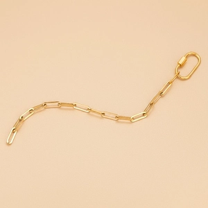 Gepolijste gouden paperclip ketting met schroefsluiting op een roze achtergrond