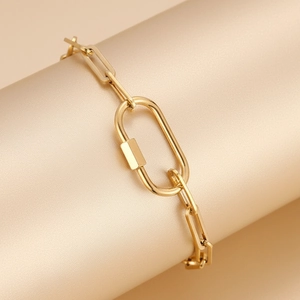 Chique gouden paperclip kettingarmband met ovale sluiting op een satijnen displaystand