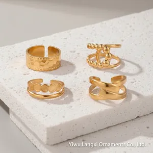 Detail of four gold adjustable stainless steel rings on a minimalist white display