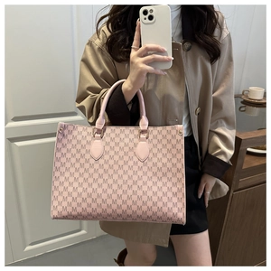 Sac fourre-tout rose avec imprimés de lettres M et anses en cuir lors d'un selfie miroir