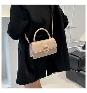 Detail of beige flap handbag with gold buckle styled on a black blazer outfit