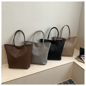 Four colors of high-capacity tote bags with woven texture displayed on a wooden surface