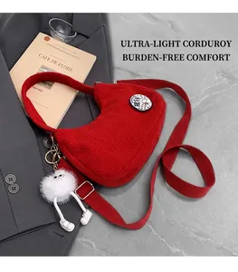 Detail of red corduroy crescent bag with cute monster charm and duck badge on blazer