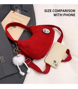 Detail of red corduroy crescent bag with a cute monster pendant and shoulder strap