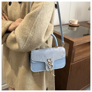 Detail of blue crossbody bag with snake pattern flap and gold fringe SS buckle