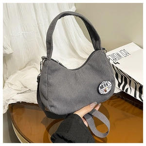 Detail view of grey corduroy shoulder bag featuring a cartoon embroidery patch