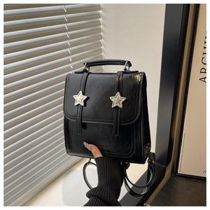 Détail d'un mini sac à dos noir en similicuir avec boucles étoiles argentées et poignée