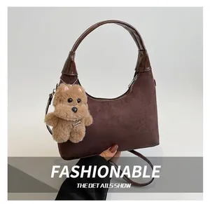 Detail of dark brown faux suede crescent bag with a cute plush dog charm accessory