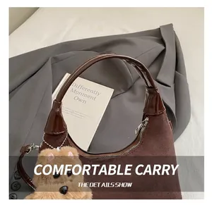 Detail of dark brown suede tote with glossy handles and a cute plush bear charm decoration