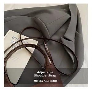Close-up of adjustable patent leather shoulder strap on a brown suede handbag