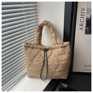 Close-up of heart quilted tote bag detailing the beige fabric and drawstring closure