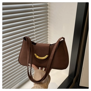Close-up of brown suede shoulder bag featuring a crescent gold metal buckle and dual straps