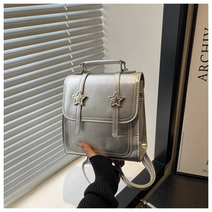 Détail d'un mini sac à dos argenté avec boucles en étoile et sangles amovibles