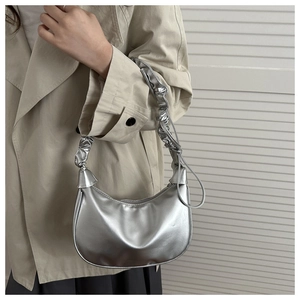Silver metallic hobo bag with pleated shoulder strap worn with a beige trench coat