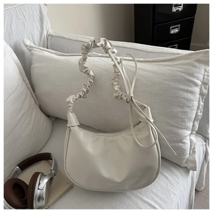 Detail of cream pleated cloud bag featuring scrunchie handle and decorative side laces
