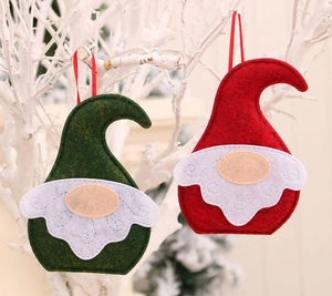 Détail de gnomes de Noël en feutre rouge et vert suspendus sur une branche d'hiver blanche
