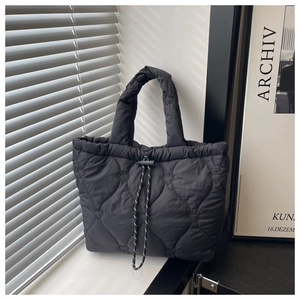 Detail of black heart-quilted tote bag featuring secure drawstring and padded handles
