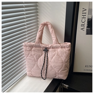 Detail of pink quilted tote bag with heart stitching and black and white drawstring